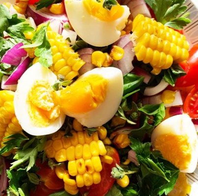 Colorful salad with corn, tomatoes, eggs, and greens