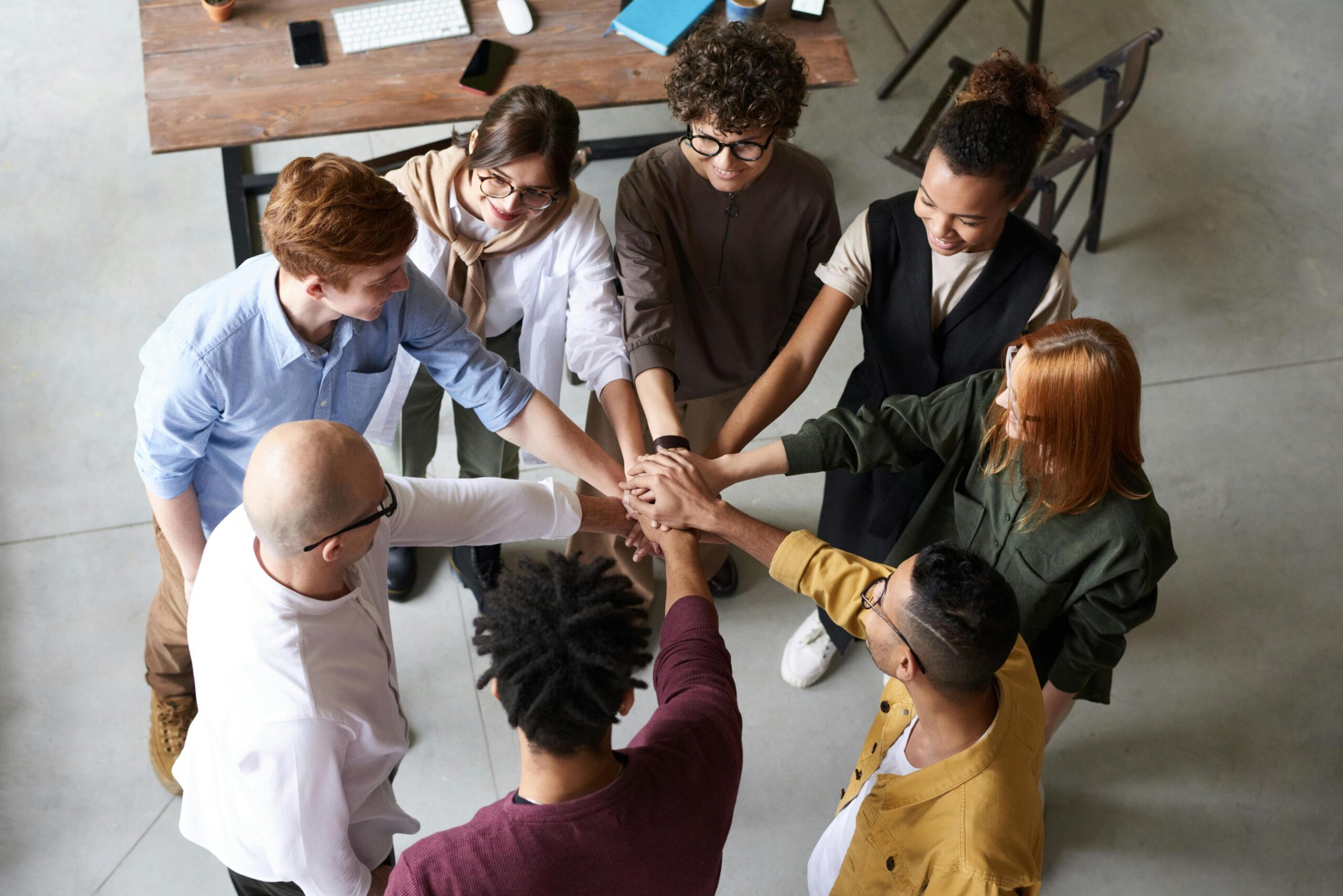 Team placing hands together in a circle as a gesture of unity