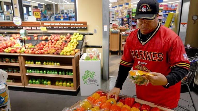 Man selecting fresh tomatoes at a grocery store produce section